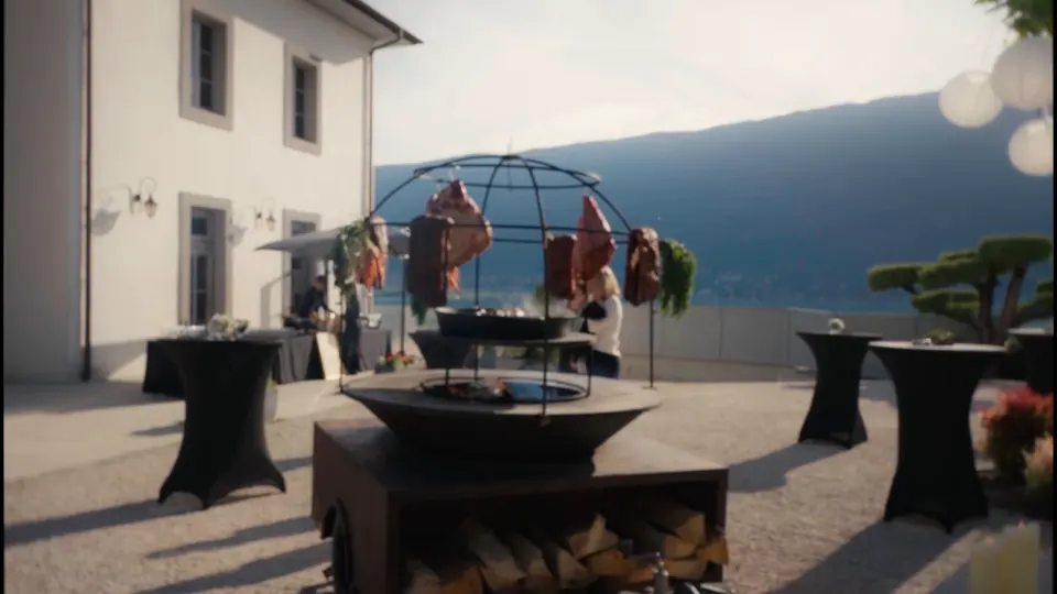 Brasero en dôme garni de viandes suspendues, sur une terrasse au bord du lac lors d'un événement BDS Events